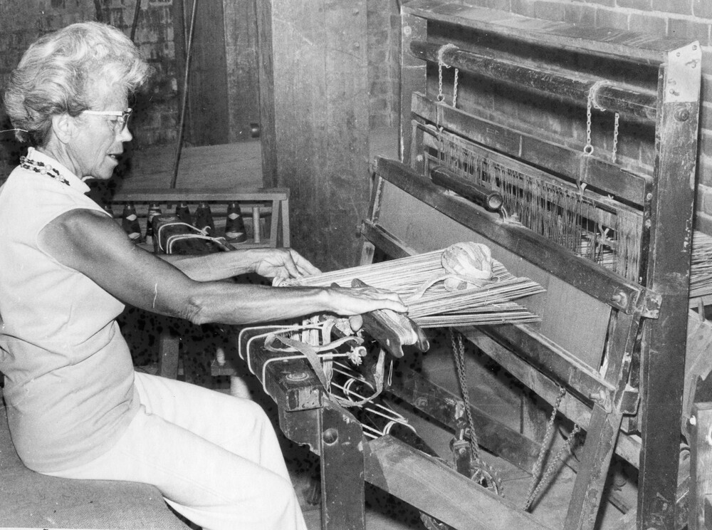 A woman working a weaving loom.