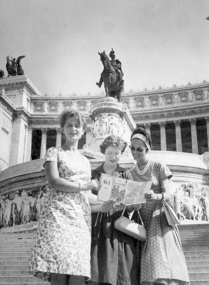 Three women in front of a monument.