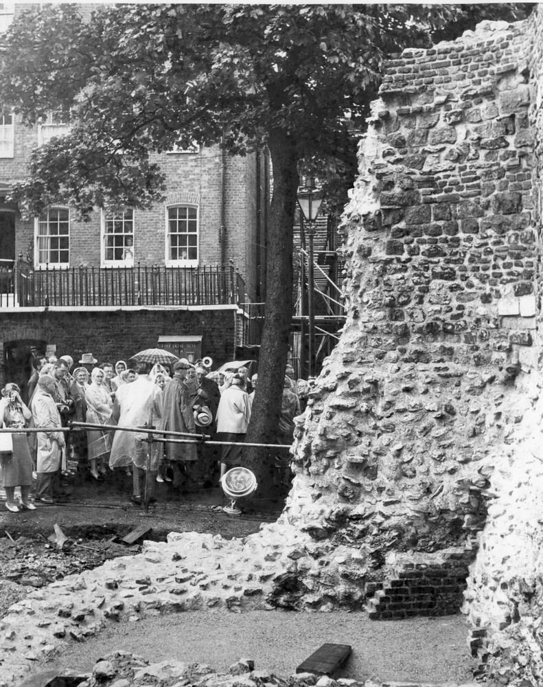 A group of people near a crumbling brick wall. 