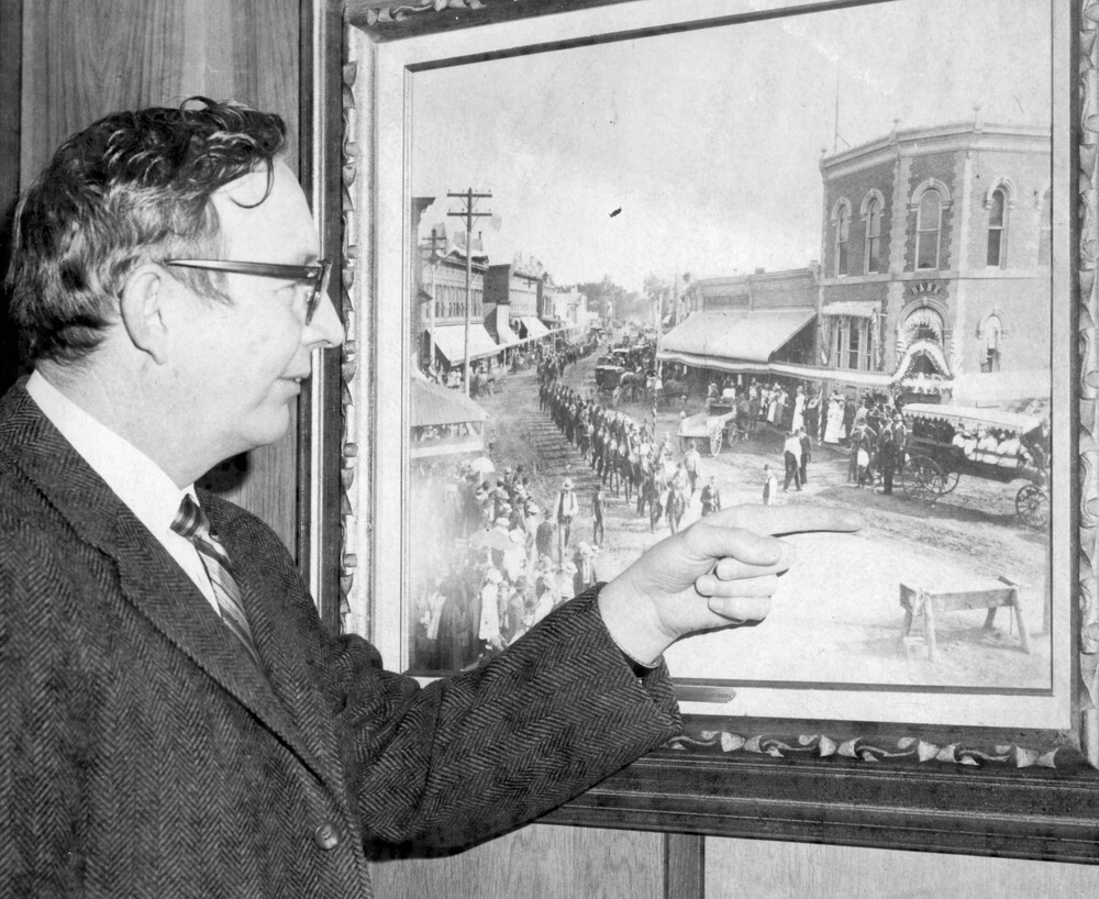 A man pointing to an old photo of a building.