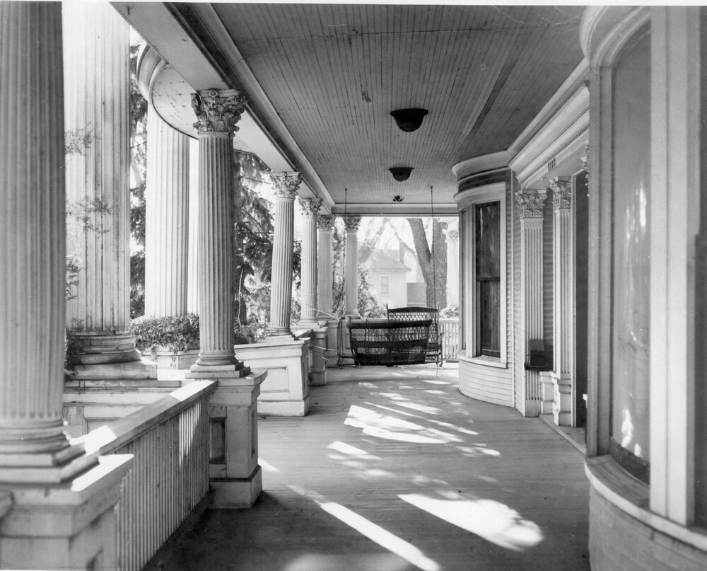 View of veranda of a mansion, featuring columns and vowed windows
