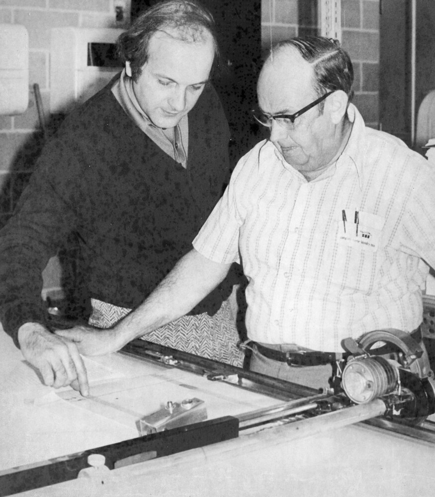 Two men looking at a piece of paper on a piece of equipment.