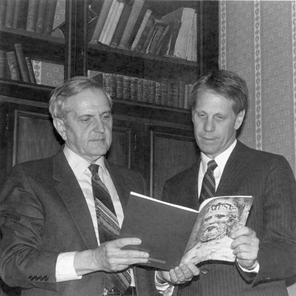 Two men reading magazine.