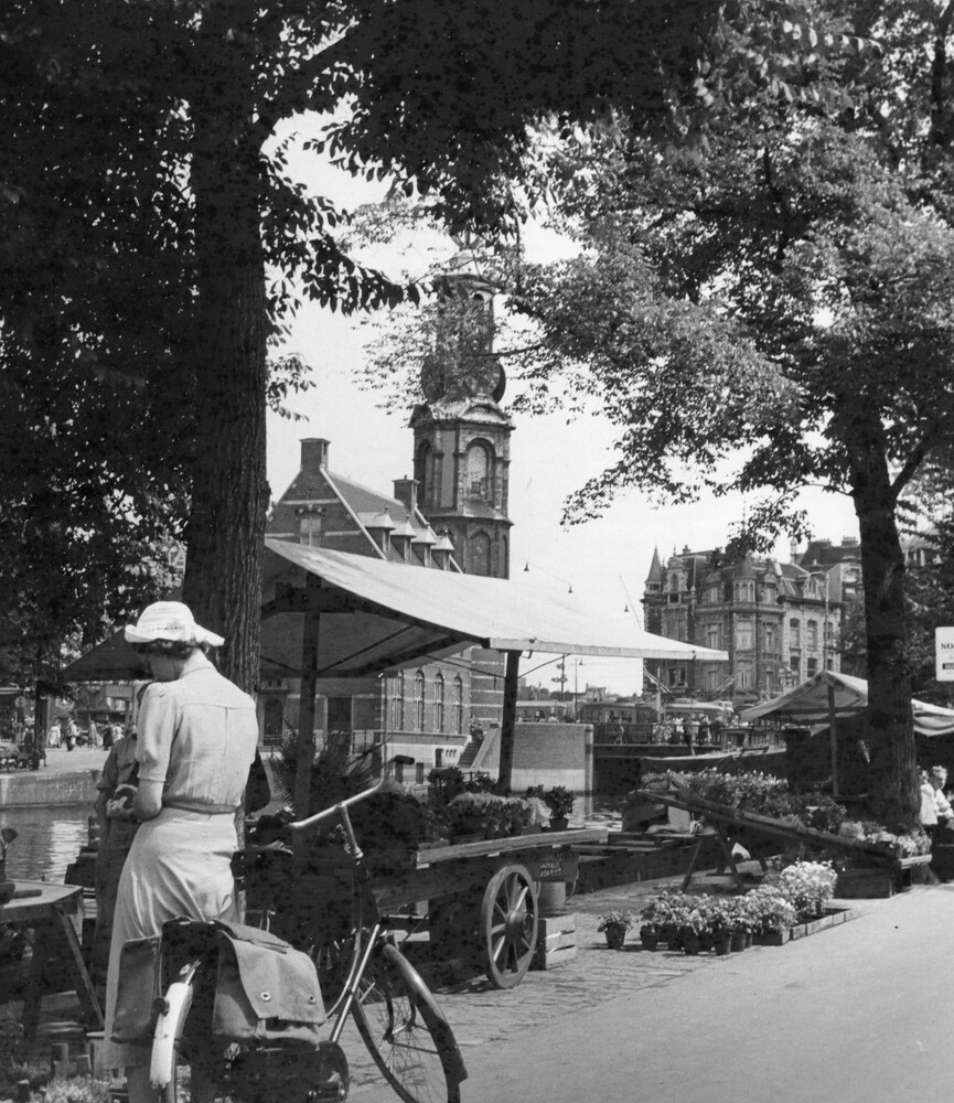 Woman with a bicycle at a large flower stall.