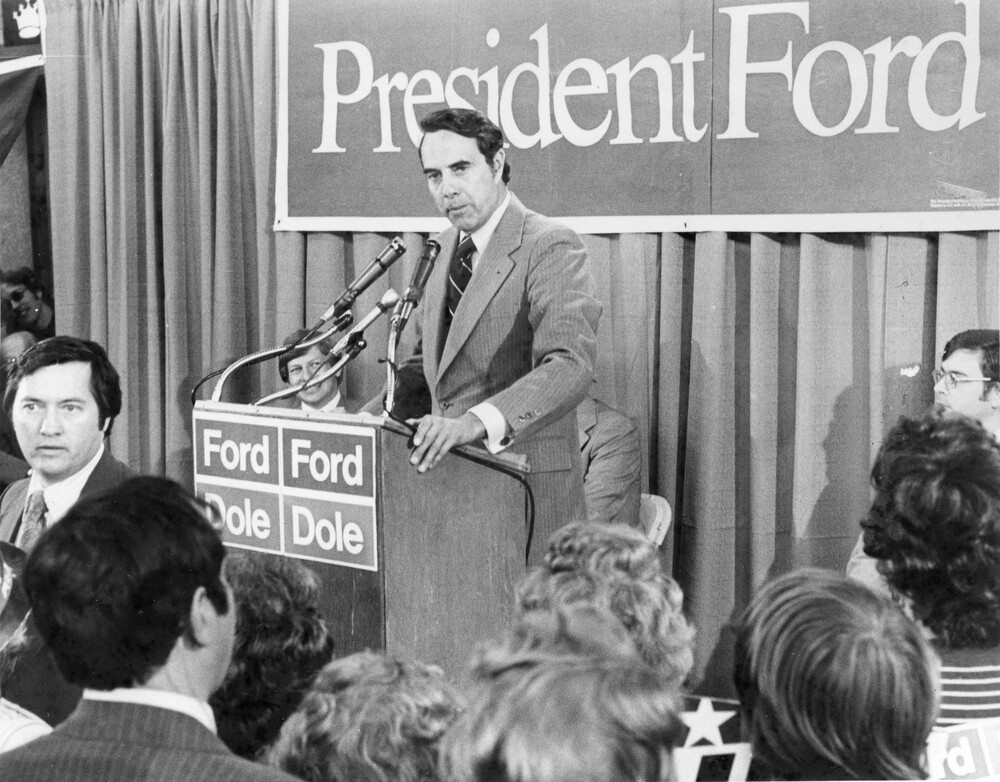 Man in suit at podium, in front of a crowd of people
