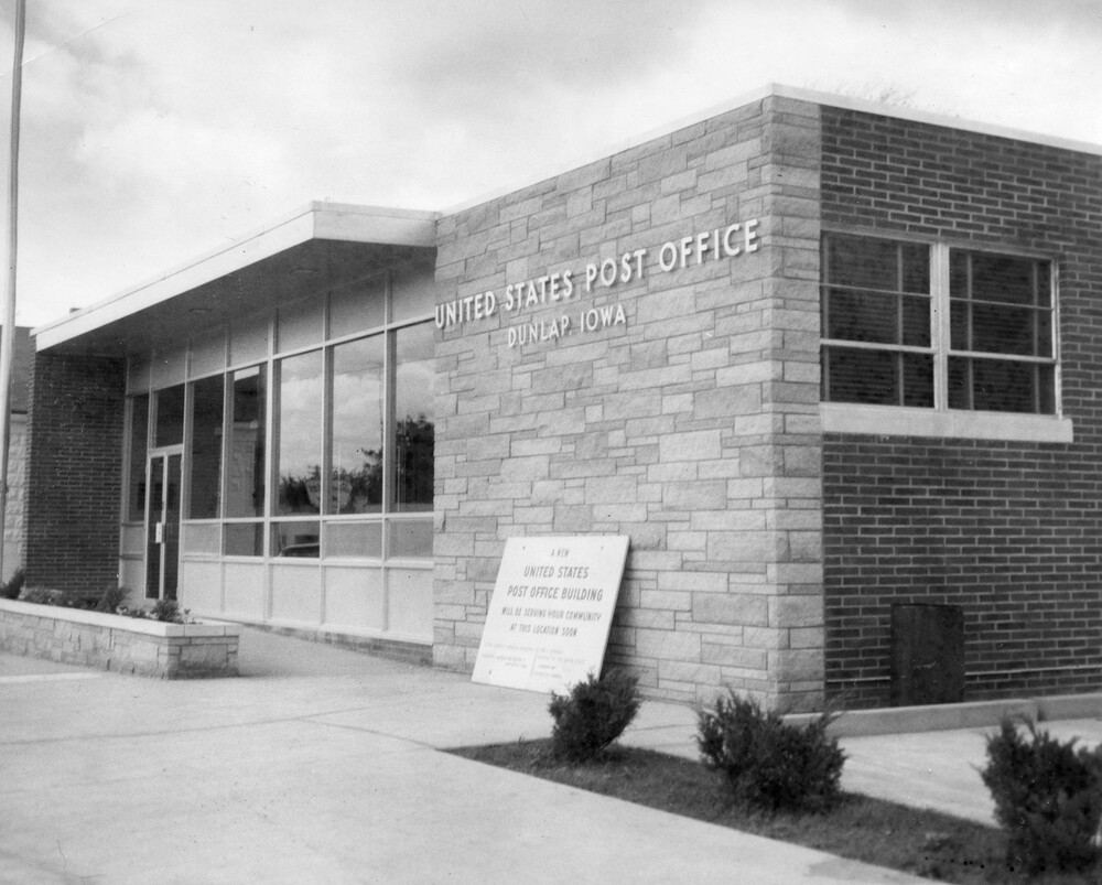 photo of one-story building of brick stone, and aluminum; "United States Post Office" is on front of stone front.