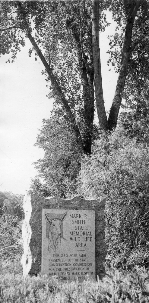 Photo of stone marker, in a wooded area, indicating a wildlife refuge