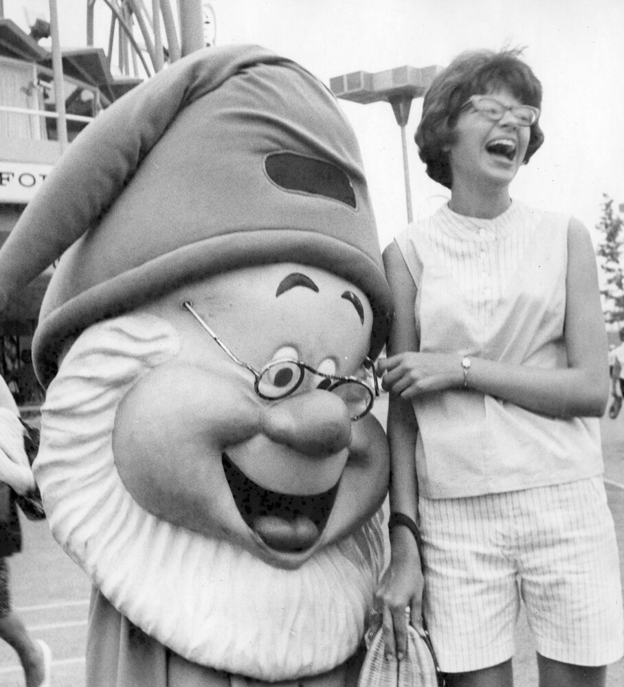 A laughing woman next to a cartoon character.