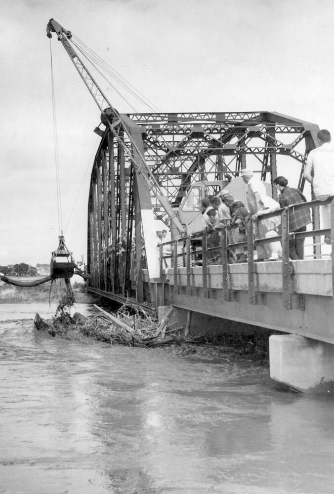Flood debris under a railroad bridge over a river.