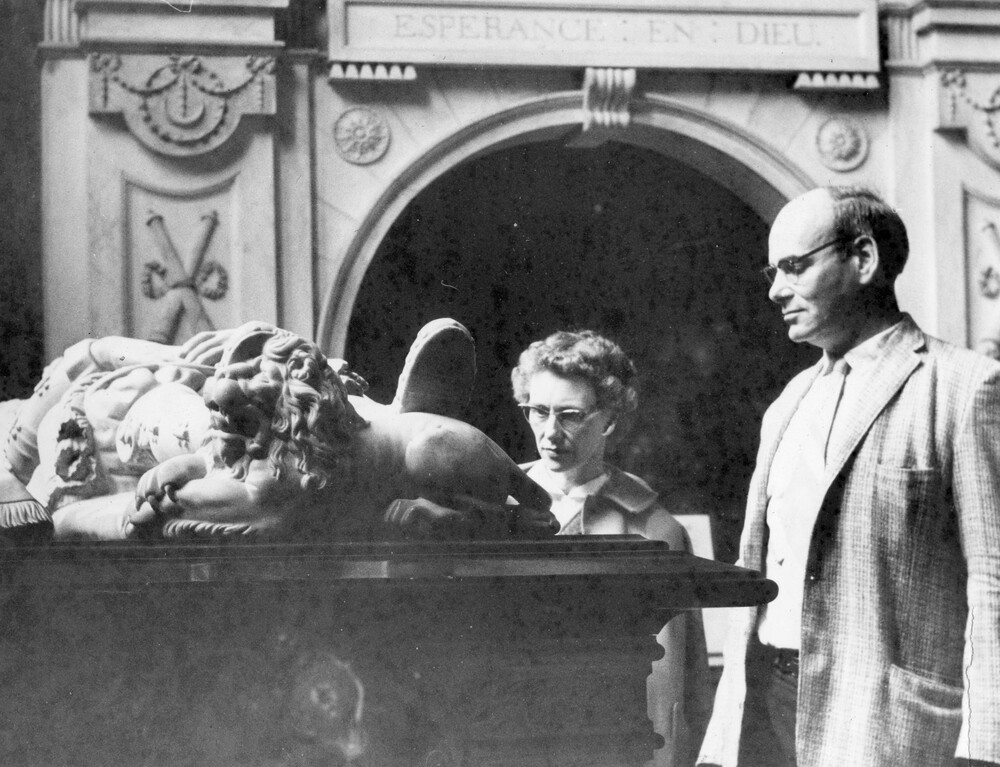Two people looking at an ornate tomb.