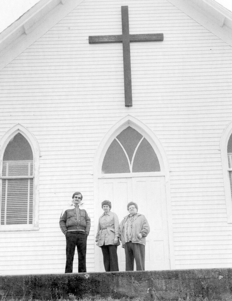 Three persons standing in front of a church.