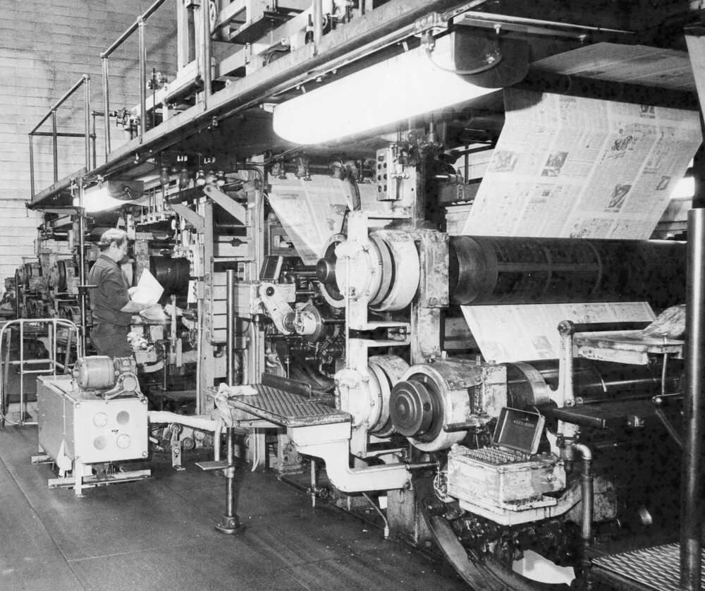 A man standing near a printing press.