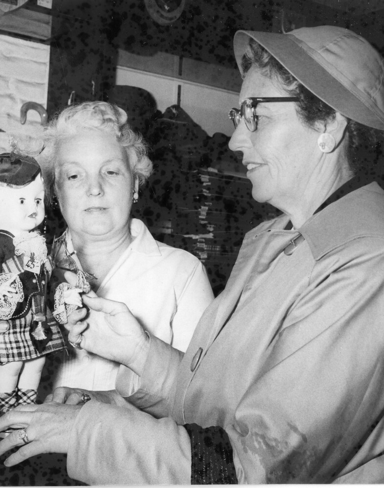 Two women viewing a doll.