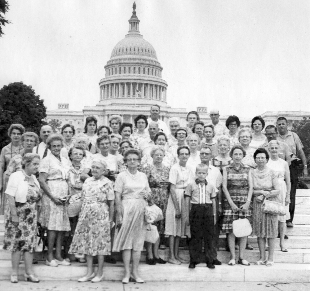 A group of tourists pose in front of the U.S. Capitol.