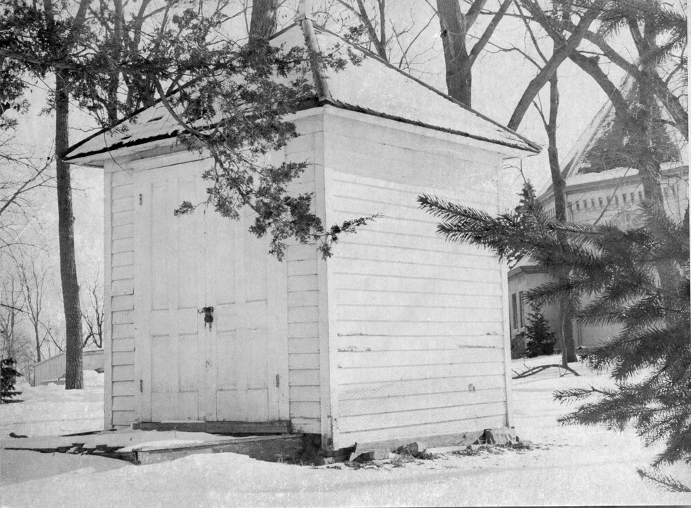 Tiny, square clapboard building with double wooden doors