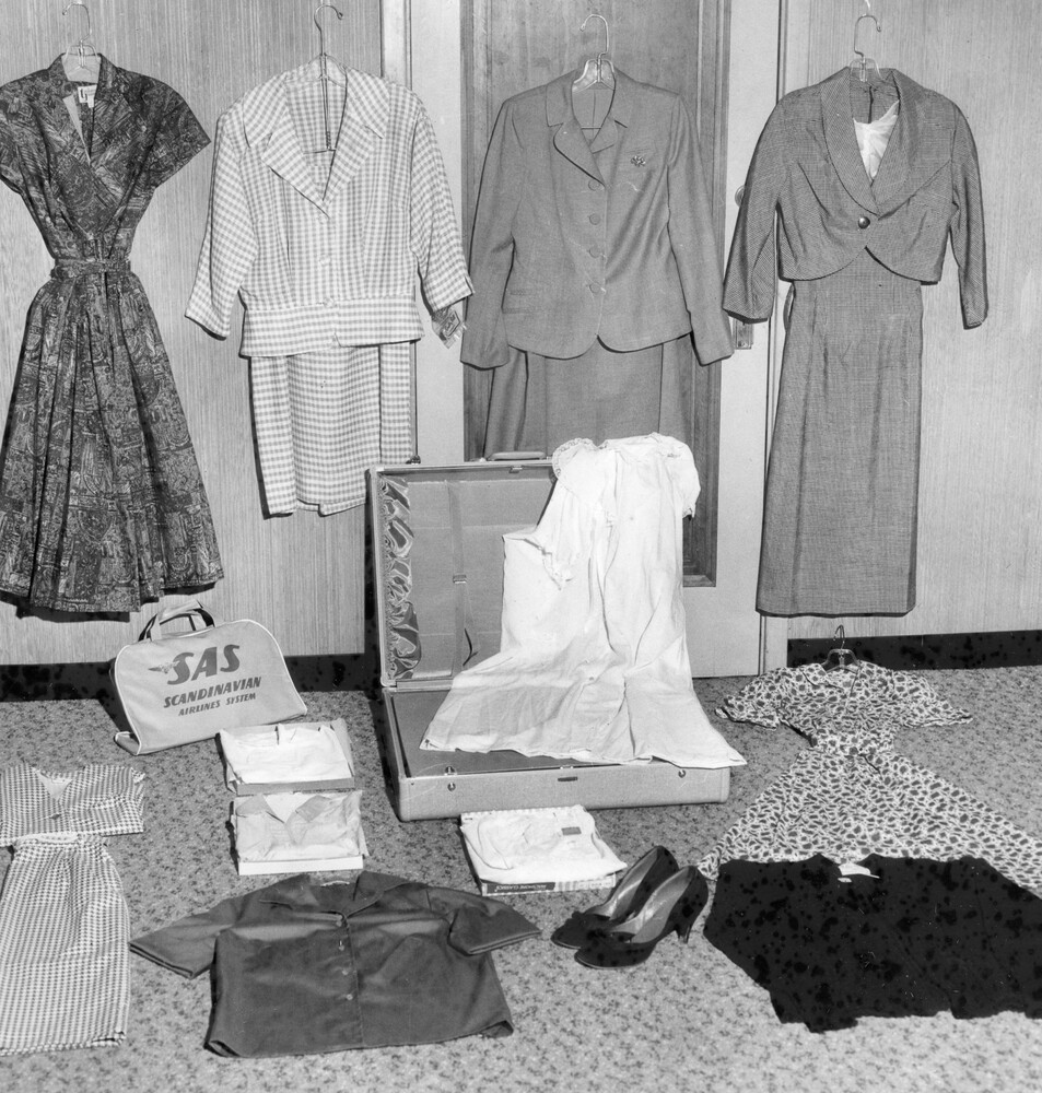 Open suitcase surrounded by women's clothing.