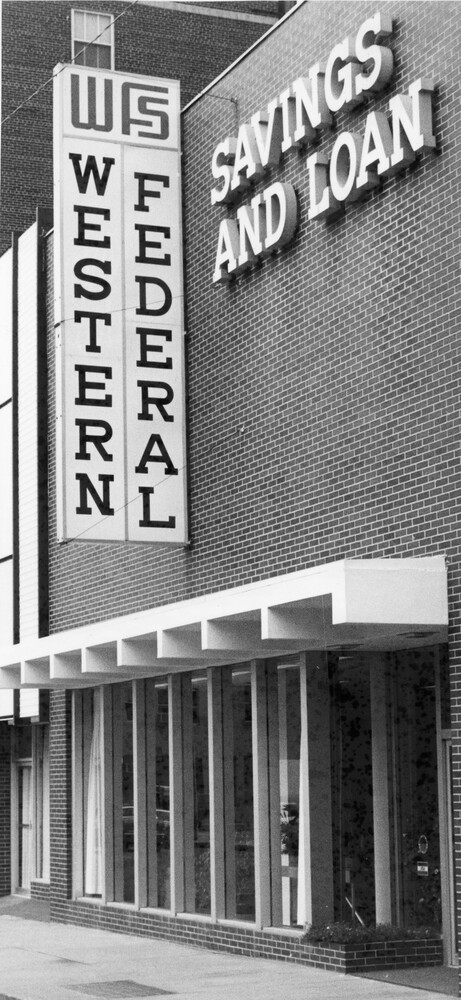 front of brick building with tall windows and architectural overhang