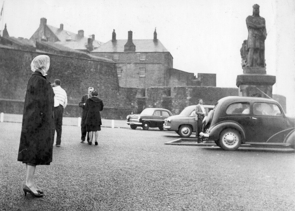 People and cars in front of a castle.