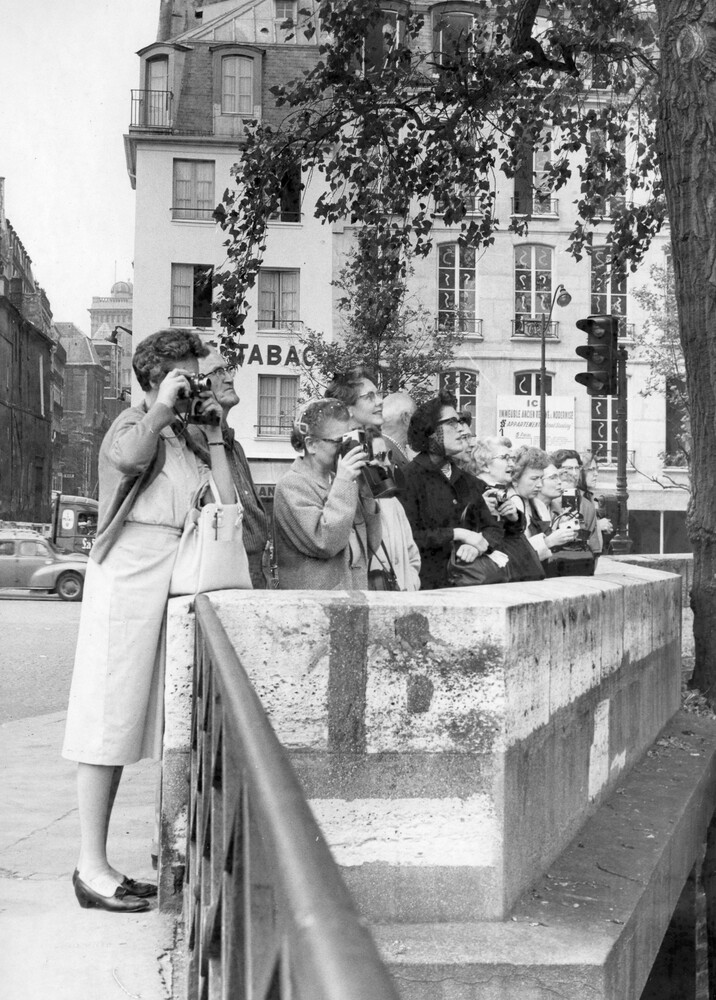 A line of women behind a barrier holding cameras.