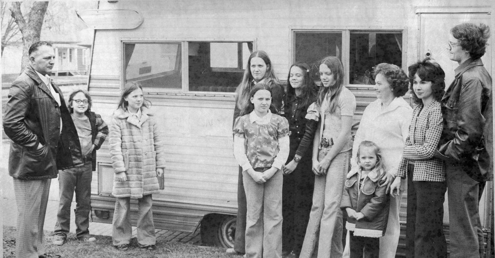 Eleven people, of various ages, next to an RV