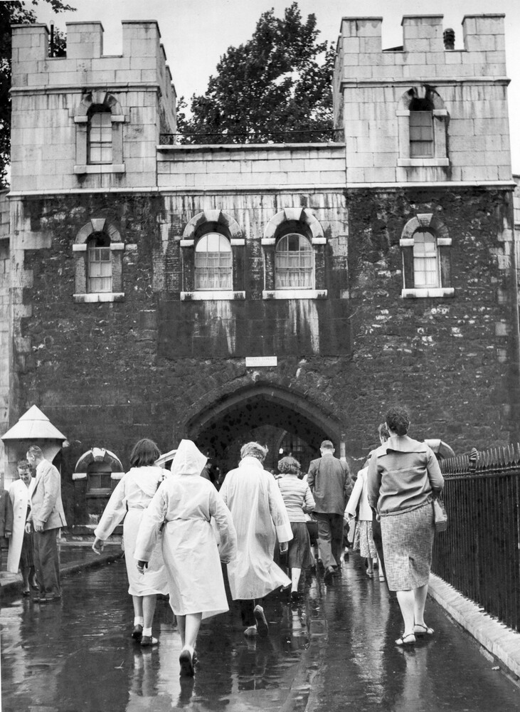 Tourists walking on a bridge under a fortress.