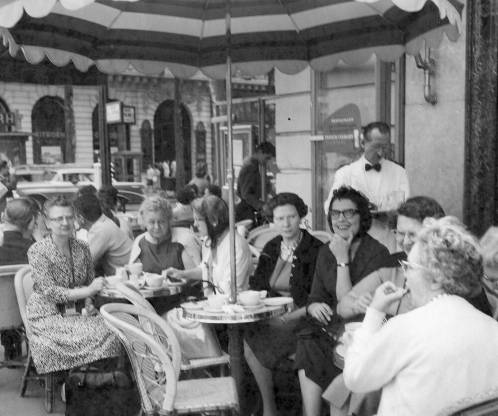 A group of women sitting outdoors under an umbrella table.
