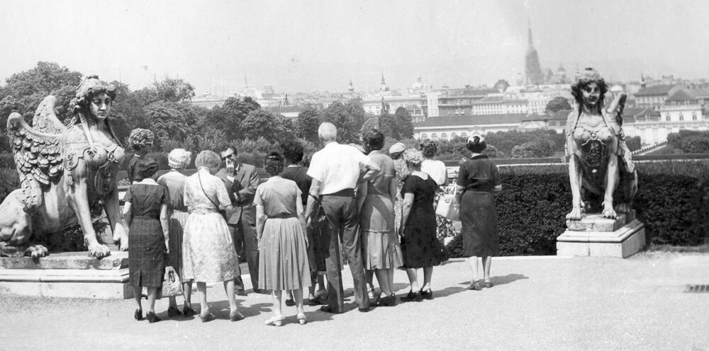 A group of people viewing gardens and buildings.