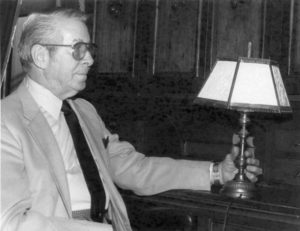 Man holding an antique lithoplane lamp.