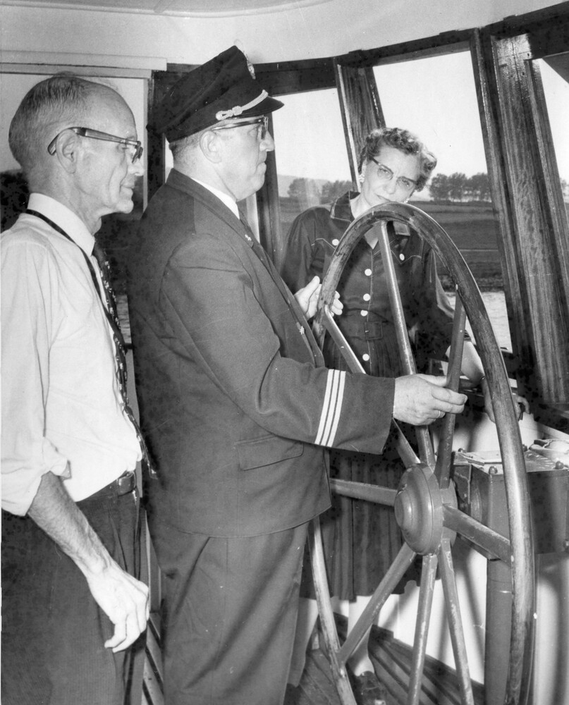 Three people at the helm of a boat.