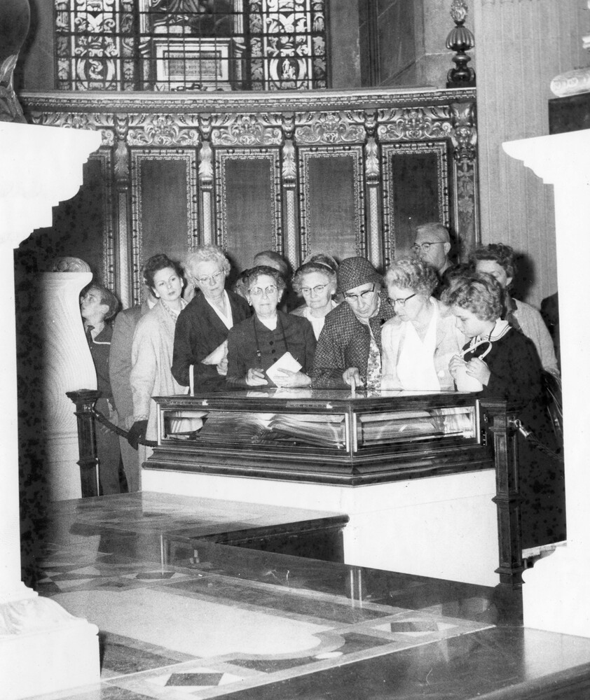 A group of women viewing a wooden and glass case.