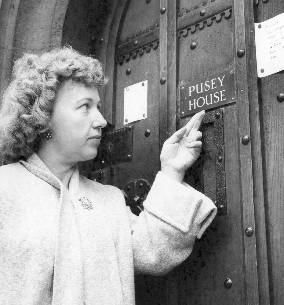 A woman pointing to a nameplate on a door.