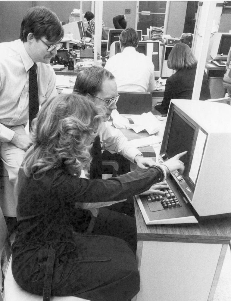 Three people looking at a computer screen.