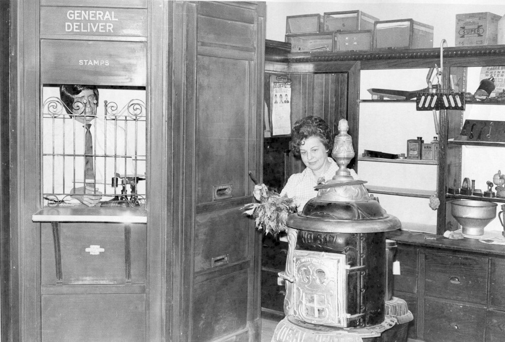 A woman dusts a pot belly stove.