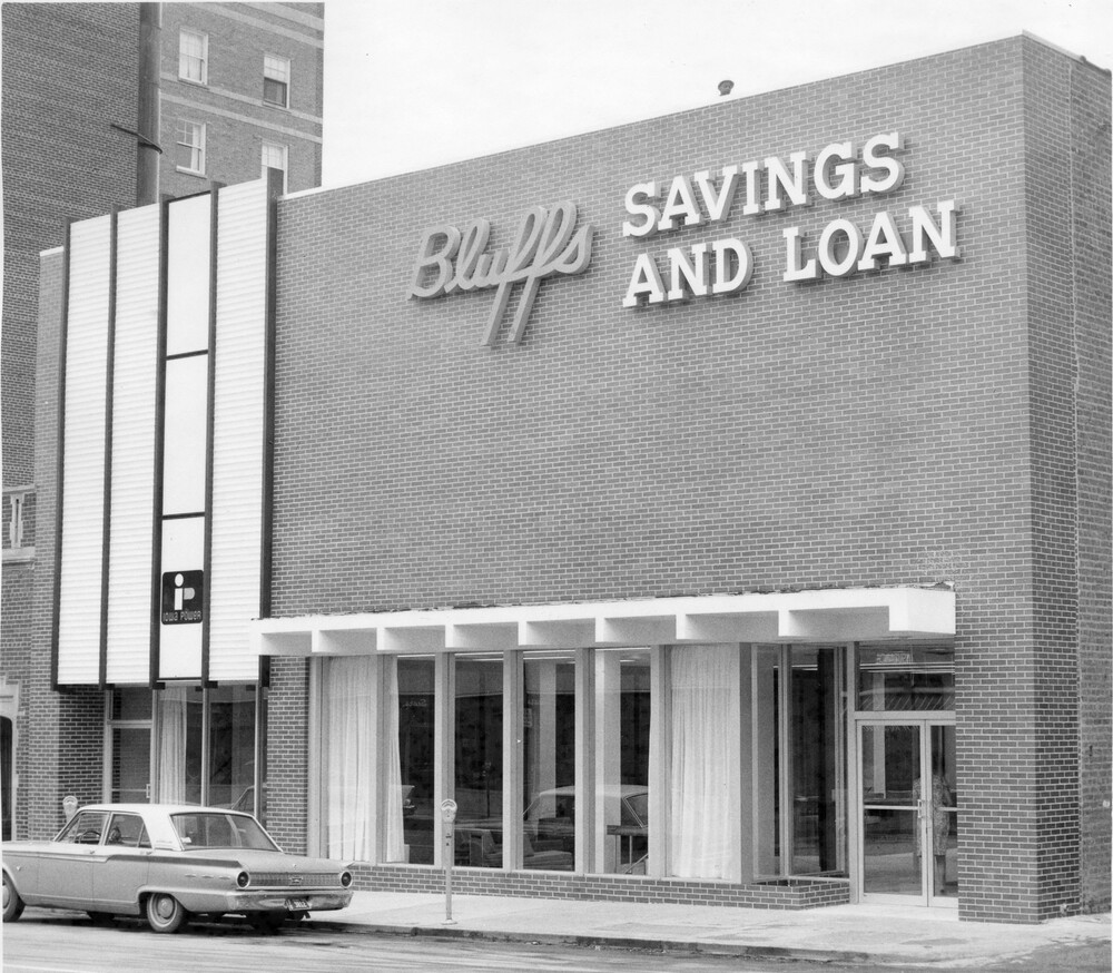 front facade of brick building with windows and overhang,  on city street