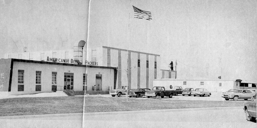 An American flag flies above a large commercial building.