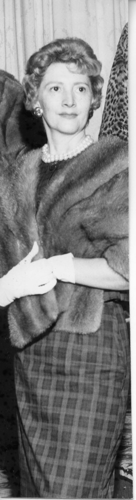 Woman wearing dress, fur jacket, pearls, and white gloves