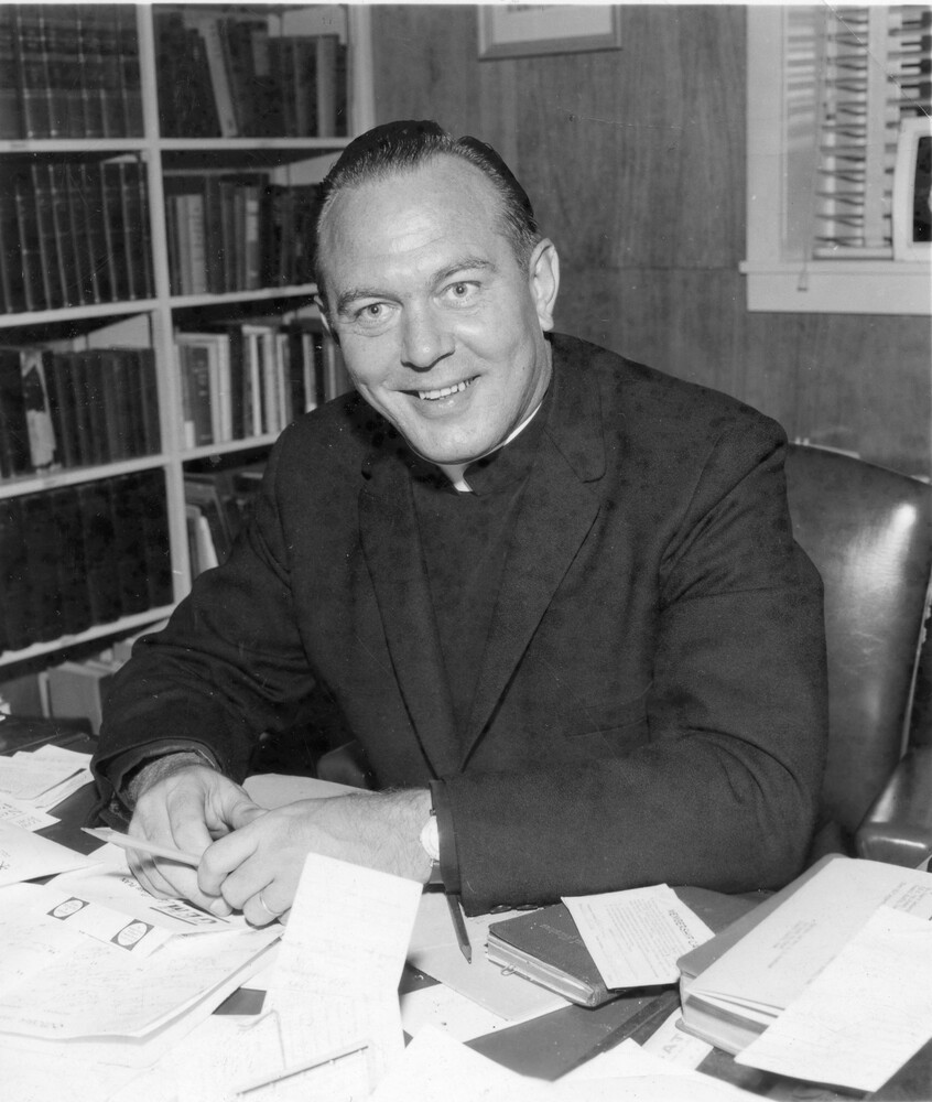 Man in clerical collar sitting at desk in an office