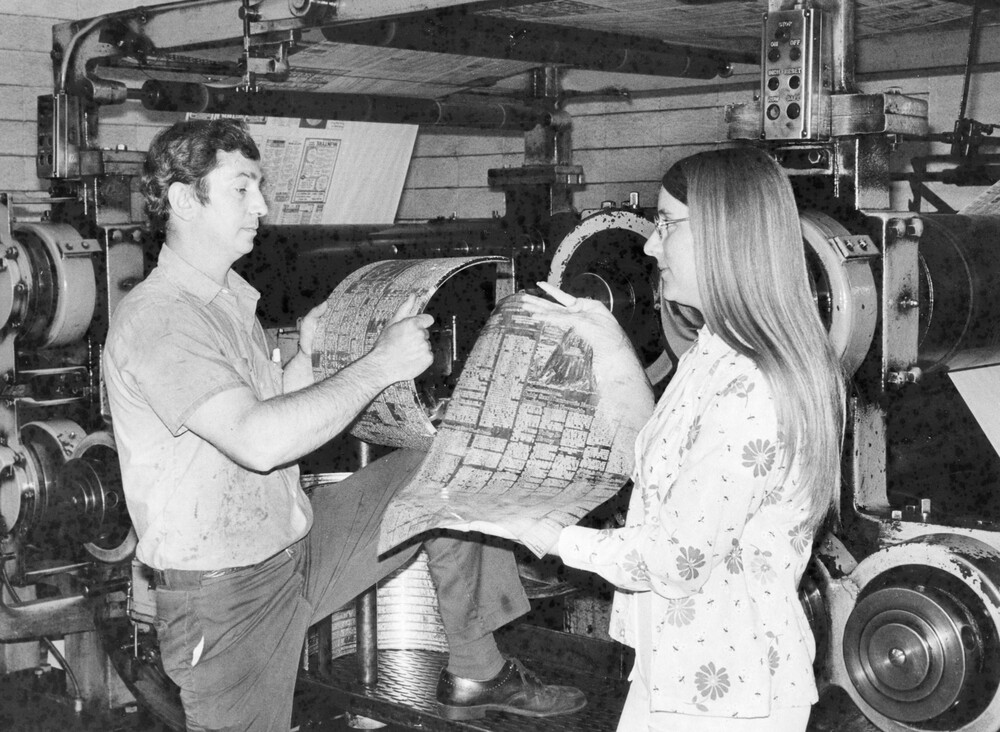Two people holding newspaper items.
