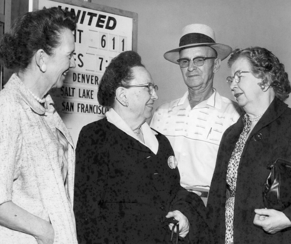 Three women and a man standing near an airline sign.