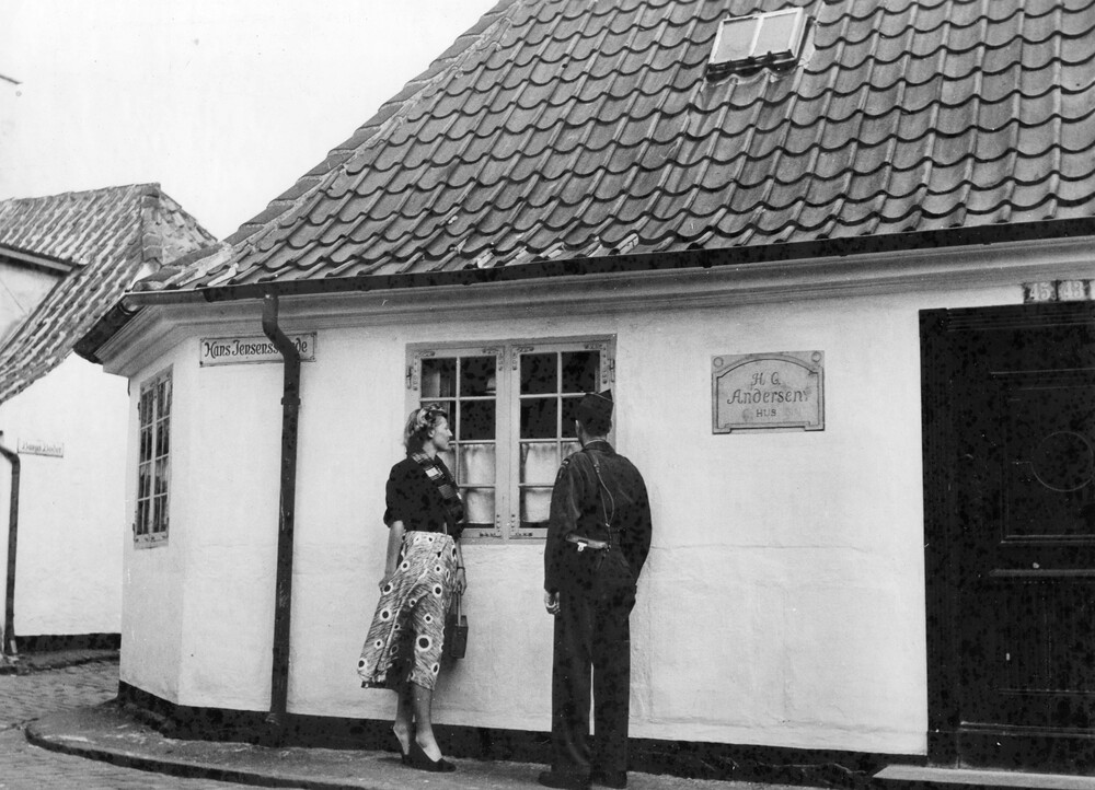 A man and woman looking through a home's window.