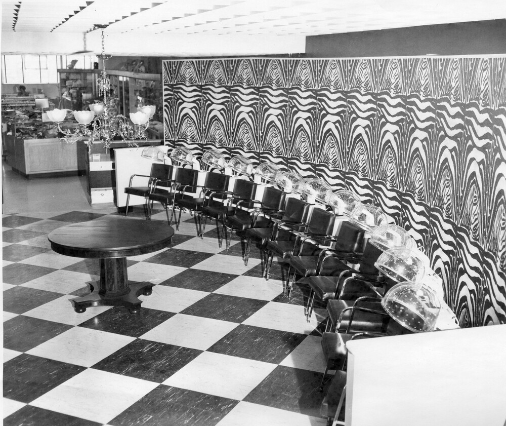 row of chairs with hair dryer hoods, along a decorated wall
