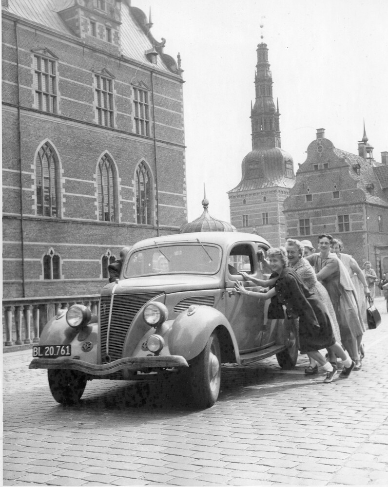 A group of women pushing a car.
