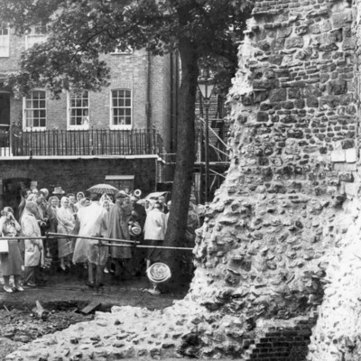 A group of people near a crumbling brick wall. 