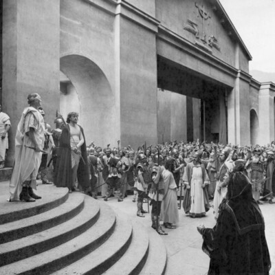 Two men standing on a theater stage in front of a crowd of people.