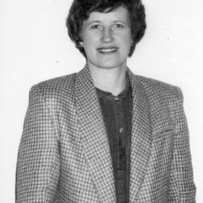 Photo of woman with short hair, wearing dark blouse and houndstooth jacket