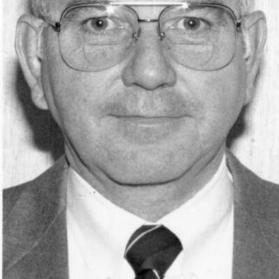 Head shot of man, wearing glasses and suit and tie