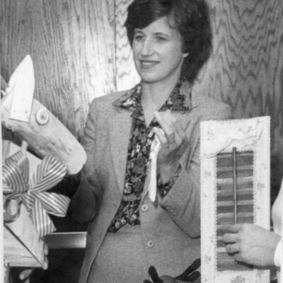 Woman in suit stands behind table of crafts