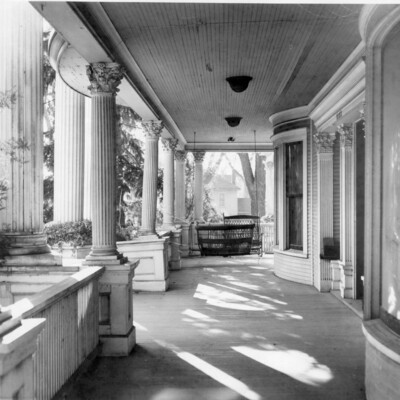 View of veranda of a mansion, featuring columns and vowed windows