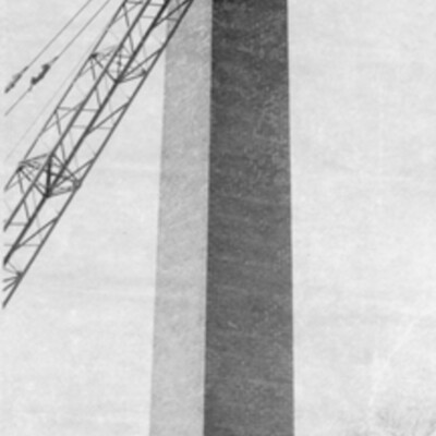 Crane with wrecking  ball in front of a brick chimney tower
