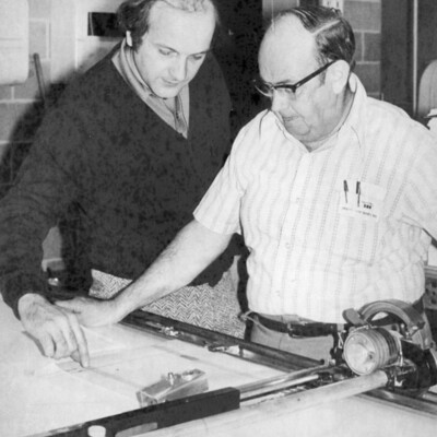 Two men looking at a piece of paper on a piece of equipment.
